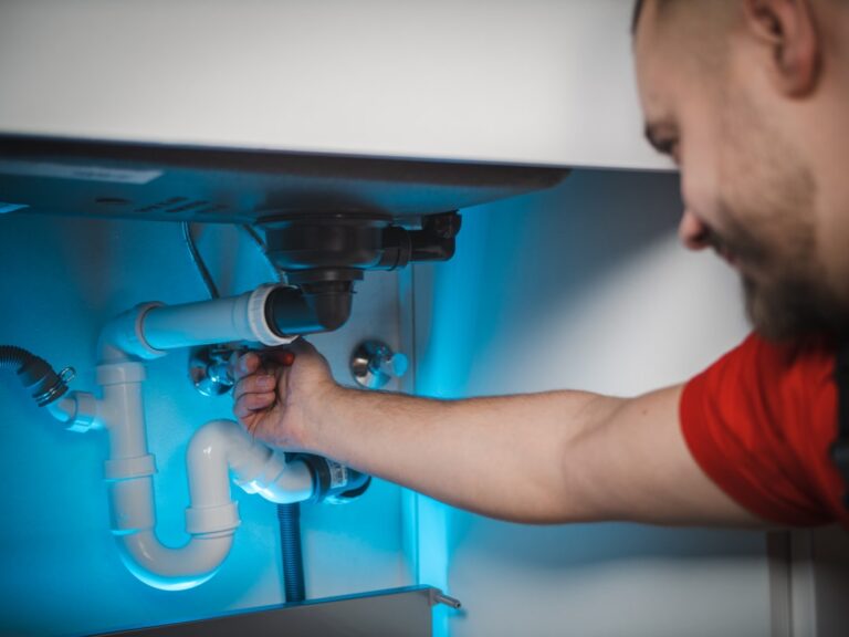 Person repairing a pipe with a wrench